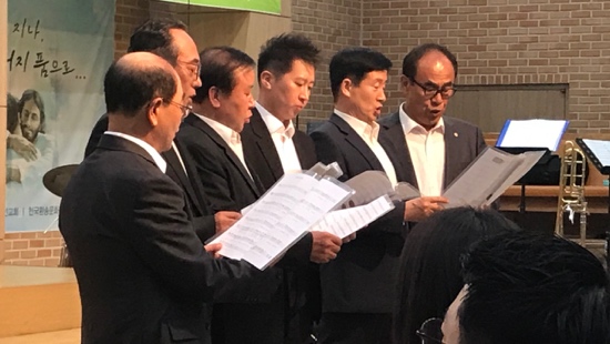 A group of men in suits holding papers
