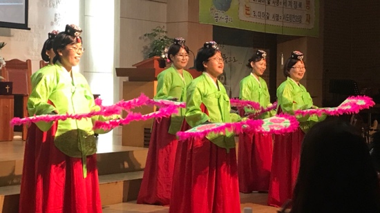 A group of women in green shirts and red skirts