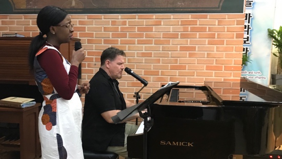 A person holding a microphone next to a person playing piano