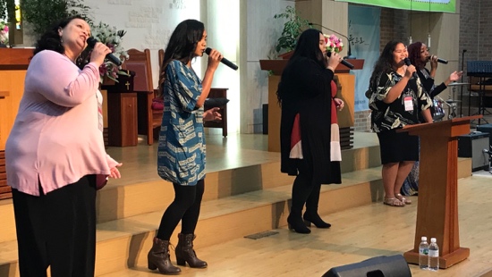 A group of women singing into microphones