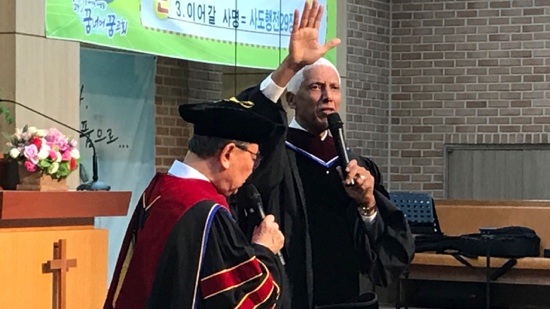 A person in graduation gown holding a microphone