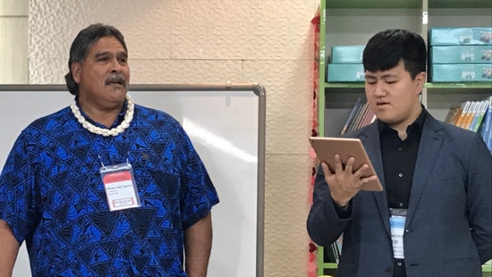 A person holding a tablet and looking at another person