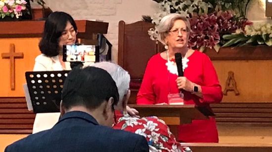A person in a red dress speaking into a microphone