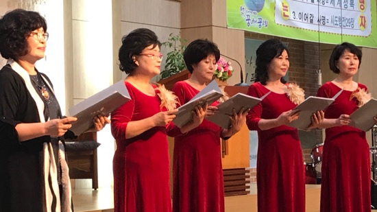 A group of women in red dresses holding papers