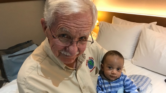 An old person with glasses and a mustache holding a baby
