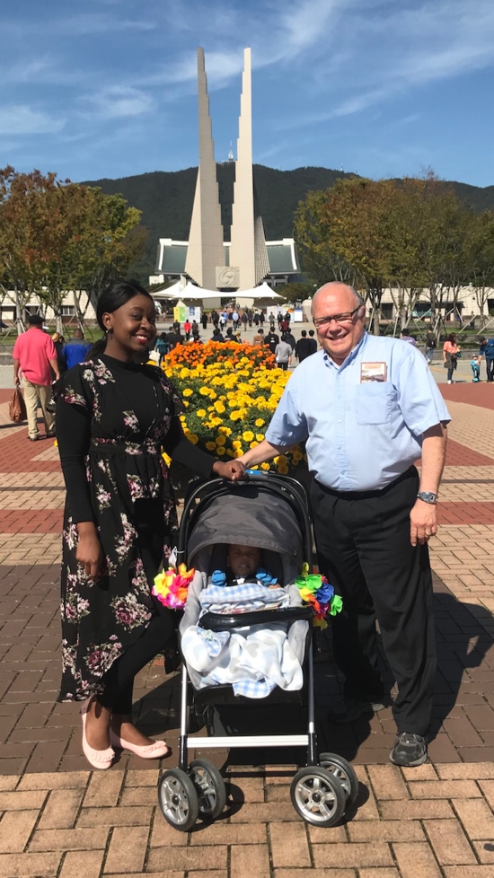 A person and person standing next to a baby in a stroller