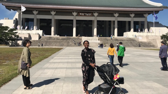 A person pushing a stroller in front of a building