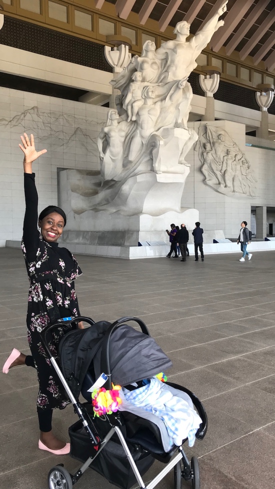 A person with her arms up in front of a statue