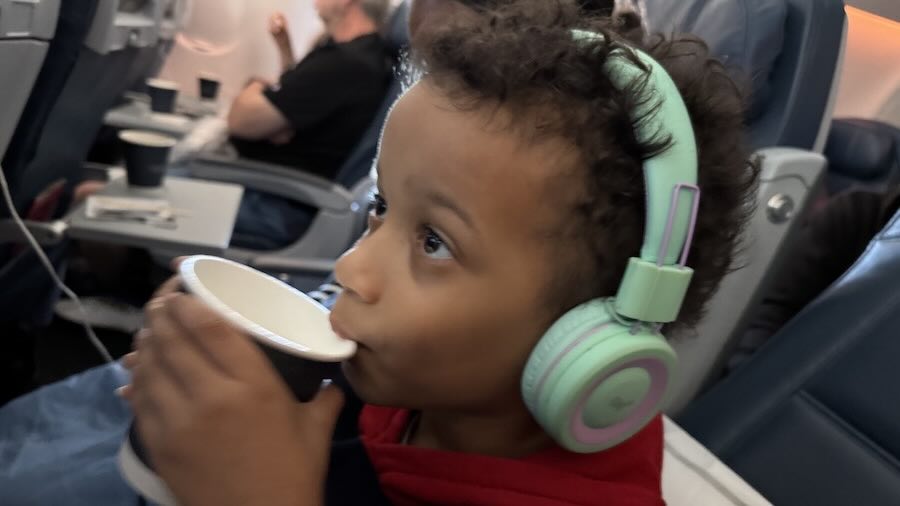 A child wearing headphones and drinking from a cup