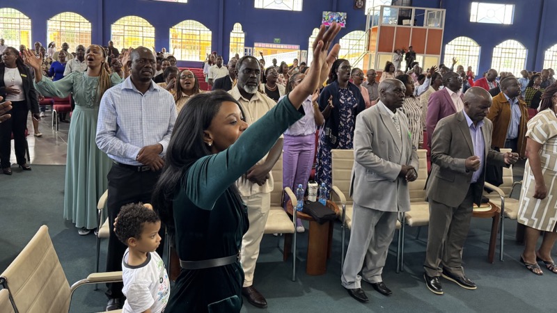 A person raising her hands in front of a crowd of people