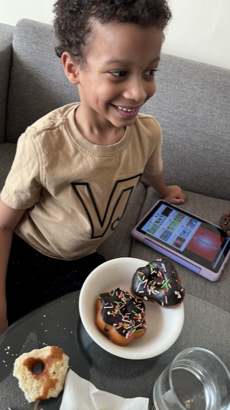 A child sitting on a couch with a bowl of donuts