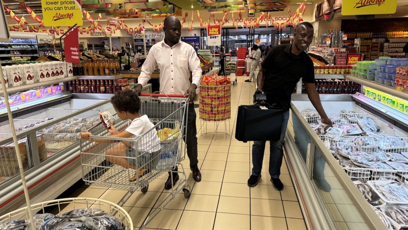 A person pushing a child in a shopping cart