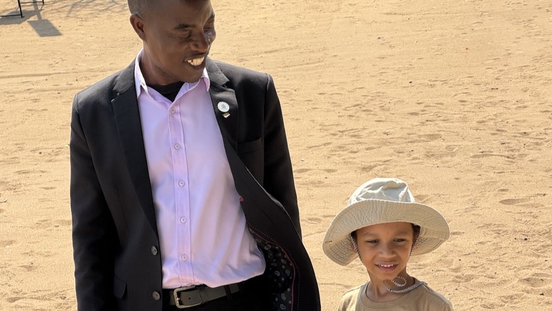A person and child standing in the sand