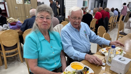 A person and person sitting at a table with food