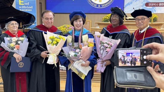 A group of people in graduation gowns holding flowers