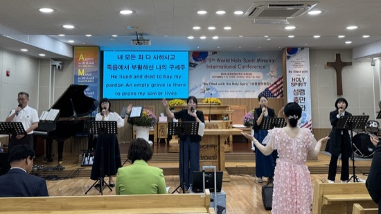 A group of people singing in front of a large screen