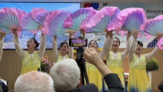A group of women holding colorful fans