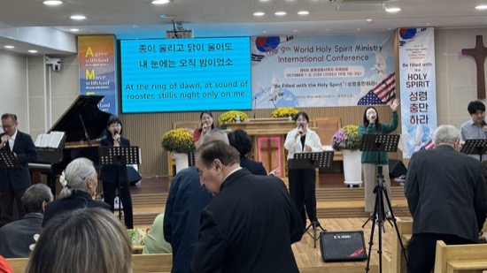 A group of people singing in front of a screen