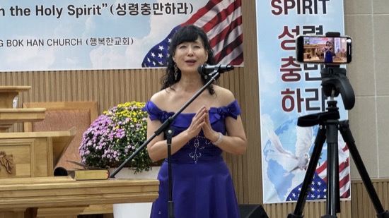 A person in a blue dress standing in front of a microphone