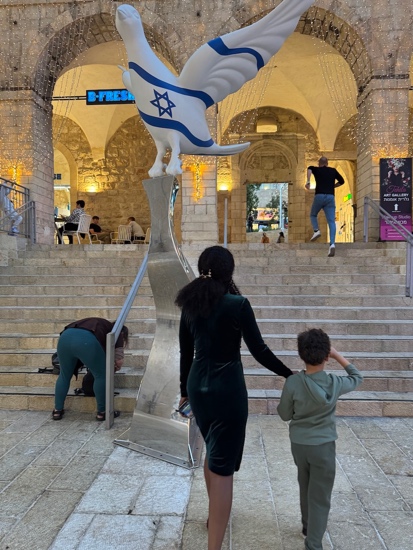 A person and a child looking at a statue of a bird