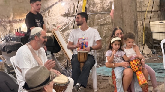 A person playing a drum with people sitting around him