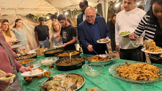 A group of people standing around a table full of food