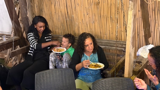 A person feeding a child to a plate of food