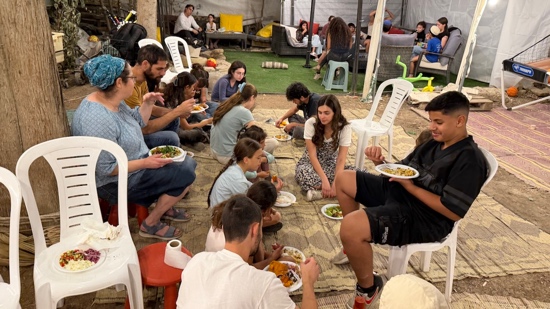 A group of people sitting on a rug eating food