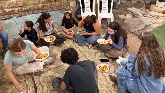 A group of people sitting on the floor eating food