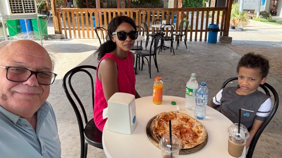 A person sitting at a table with a pizza and drinks