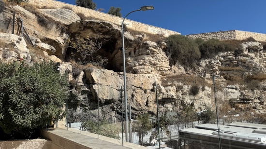 A rock wall with a light post and trees with medium confidence