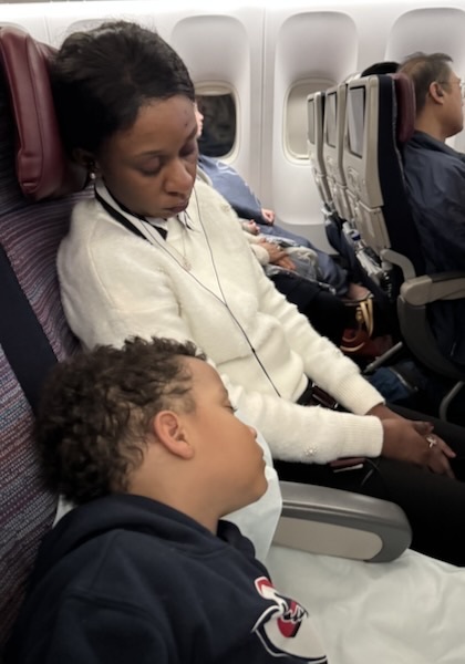 A person and a child sleeping on an airplane