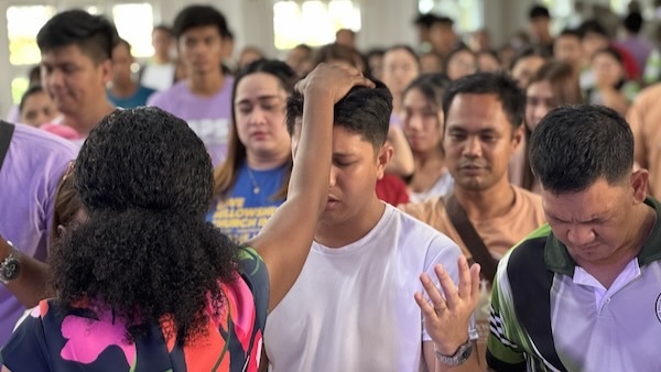 A person holding his head in front of a crowd