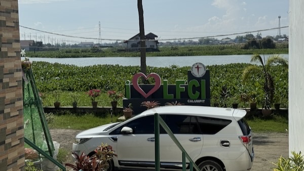 A white car parked in front of a sign