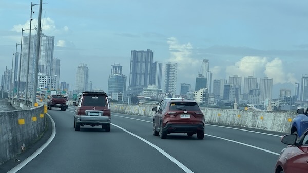 Cars driving on a highway with a city in the background