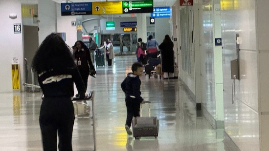 A child pushing a suitcase in an airport

Description automatically generated