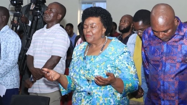 A person with eyes closed standing in front of a crowd