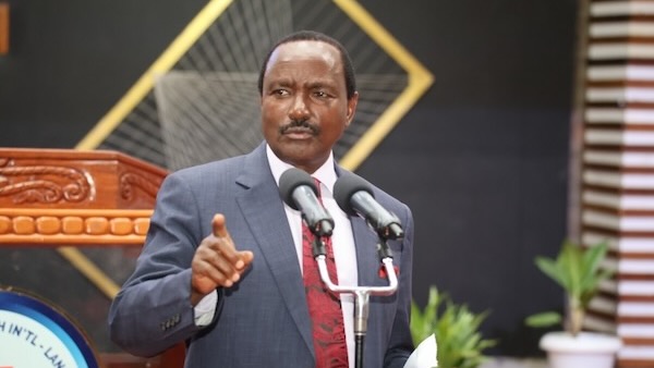 A person in a suit and tie speaking into microphones