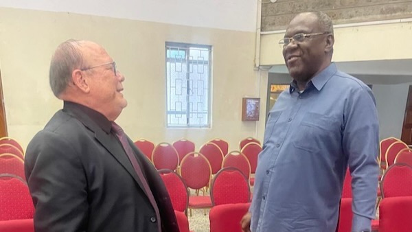 Two men in a room with red chairs