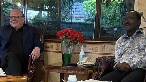 A person and person sitting in chairs and a vase of red flowers