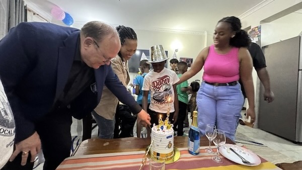 A person standing around a birthday cake with a child in the background