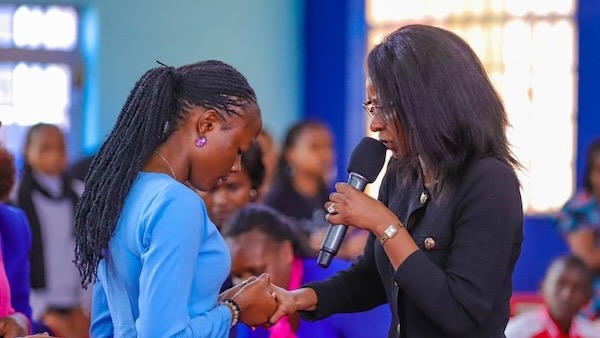 A person holding a microphone and another person holding her hands