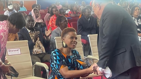 A person sitting in a chair shaking hands with a person in a suit