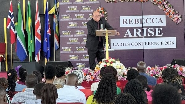 A person standing at a podium with a crowd of people