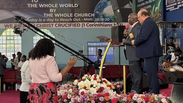 A group of people standing in front of a podium with flowers