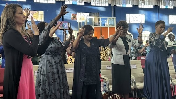 A group of women standing in a room with their hands up