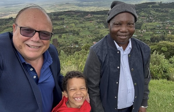 A group of men standing together with a child in front of a landscape