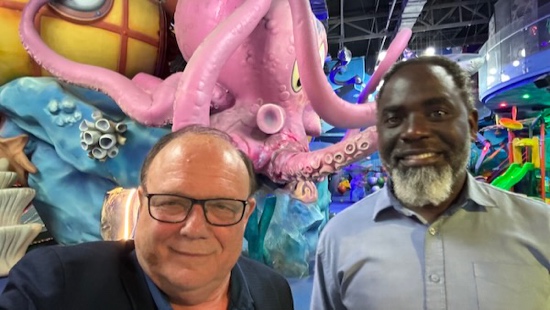 Two men standing in front of a pink octopus statue