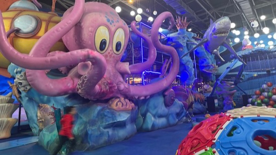 A group of people walking in a room with a large display of octopus