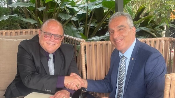 Two men shaking hands sitting at a table